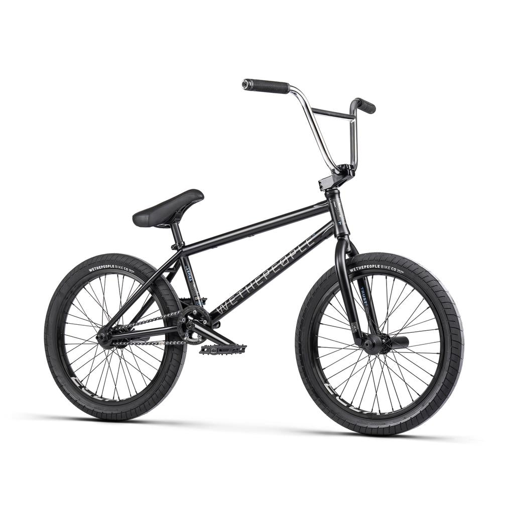 The Wethepeople Trust 20 Inch Cassette/Hybrid Bike features thick tires, straight handlebars, a padded seat, pedal system, and Eclat Shift Freecoaster Hub for smooth performance. Shown in black with 20-inch wheels on a white background.