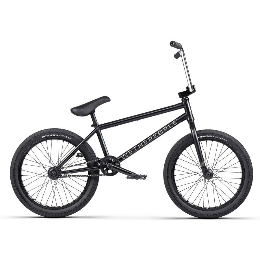 The Wethepeople Trust 20 Inch Freecoaster/Hybrid Bike features a sleek design with battleship geometry, black tires, and a high-rise handlebar, displaying "WeThePeople" on its black frame.