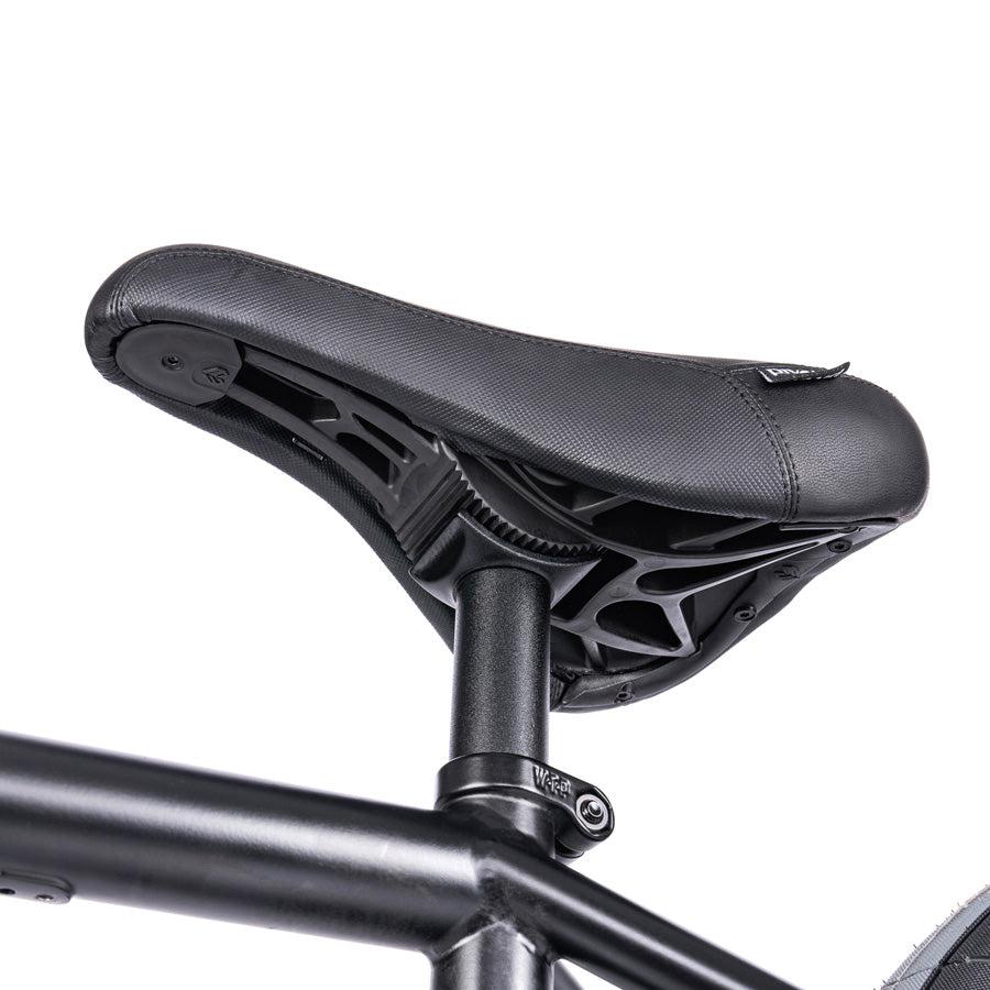 Close-up of the Wethepeople Trust 20 Inch Freecoaster/Hybrid Bike's black seat with a modern design on a black metal frame, reminiscent of sleek BMX bike aesthetics.