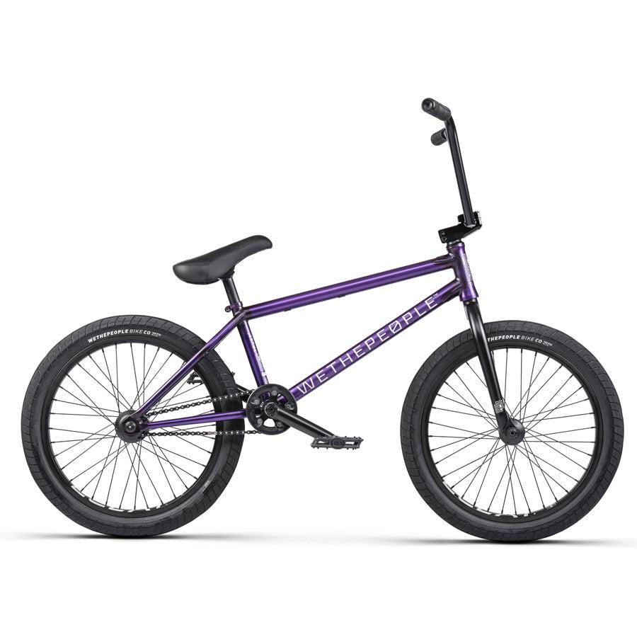 The Wethepeople Trust 20 Inch Freecoaster/Hybrid Bike comes in a purple finish with black handlebars, seat, and tires. The frame proudly displays "WETHEPEOPLE" branding and features battleship geometry to enhance its sleek design for superior performance.