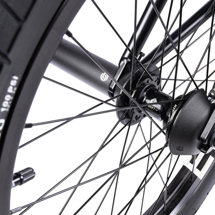 Close-up of a Wethepeople Trust 20 Inch Freecoaster/Hybrid Bike wheel, highlighting its sleek black spokes and central hub against a white background, capturing the essence of battleship geometry.
