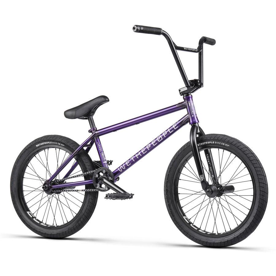 The Wethepeople Trust 20 Inch Freecoaster/Hybrid Bike comes in purple, featuring battleship geometry with black handlebars and tires, and is adorned with white brand text on the frame.