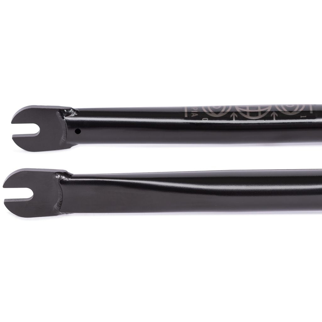 The Wethepeople Utopia Zero Flatland Fork, a pair of black metal bicycle forks with zero-offset dropouts, rests against a white background, ideal for BMX flatland riders wanting precision and style.