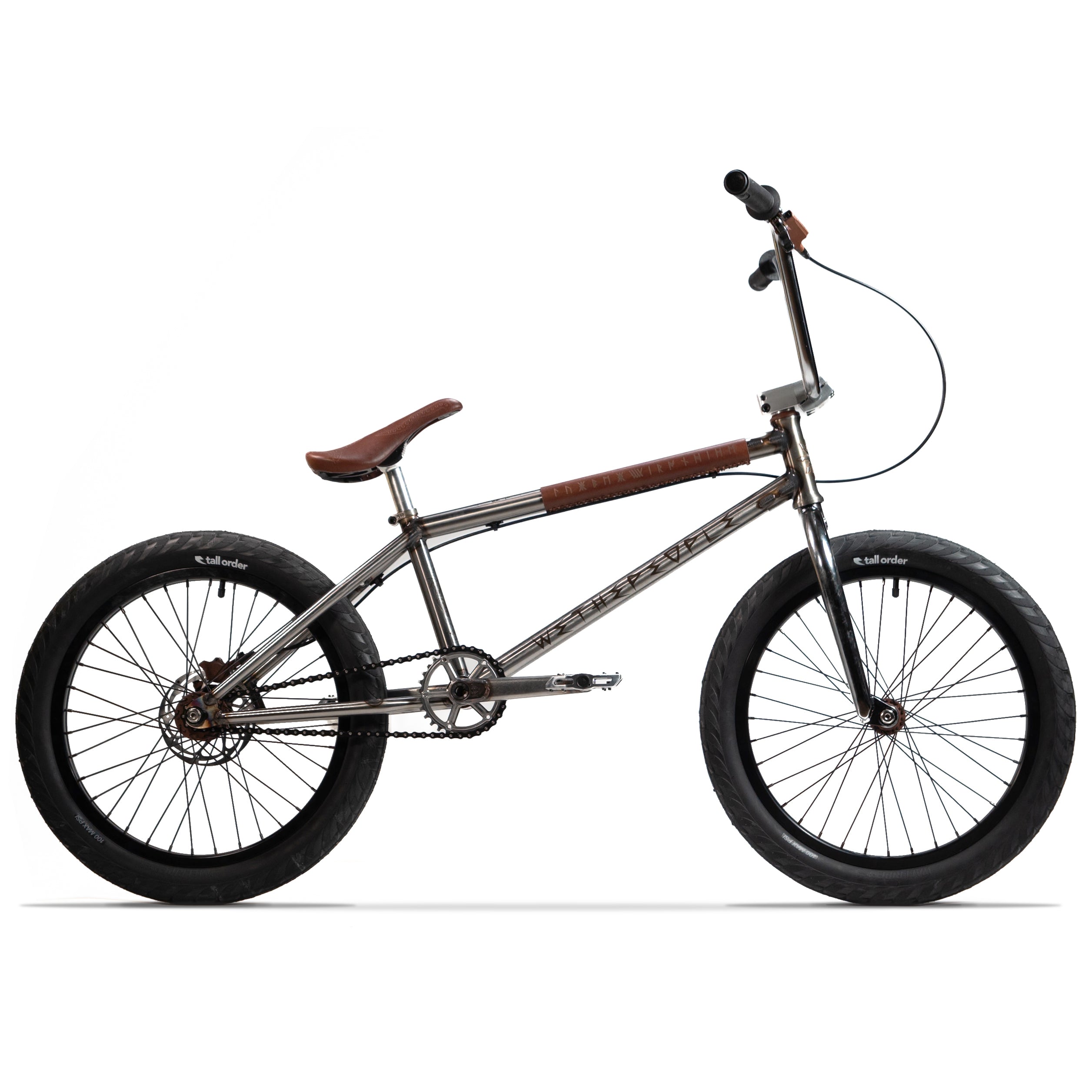 Introducing the Wethepeople X LUX LAB 'Ironhide' Chaos Machine 20 Inch Custom Bike: a silver BMX equipped with a durable frame, responsive pedals, and a robust chain. It features prominent black tires branded with "Salt Tracer," brown grips, a matching brown saddle, and cutting-edge Eclat Controller Bars for superior handling.