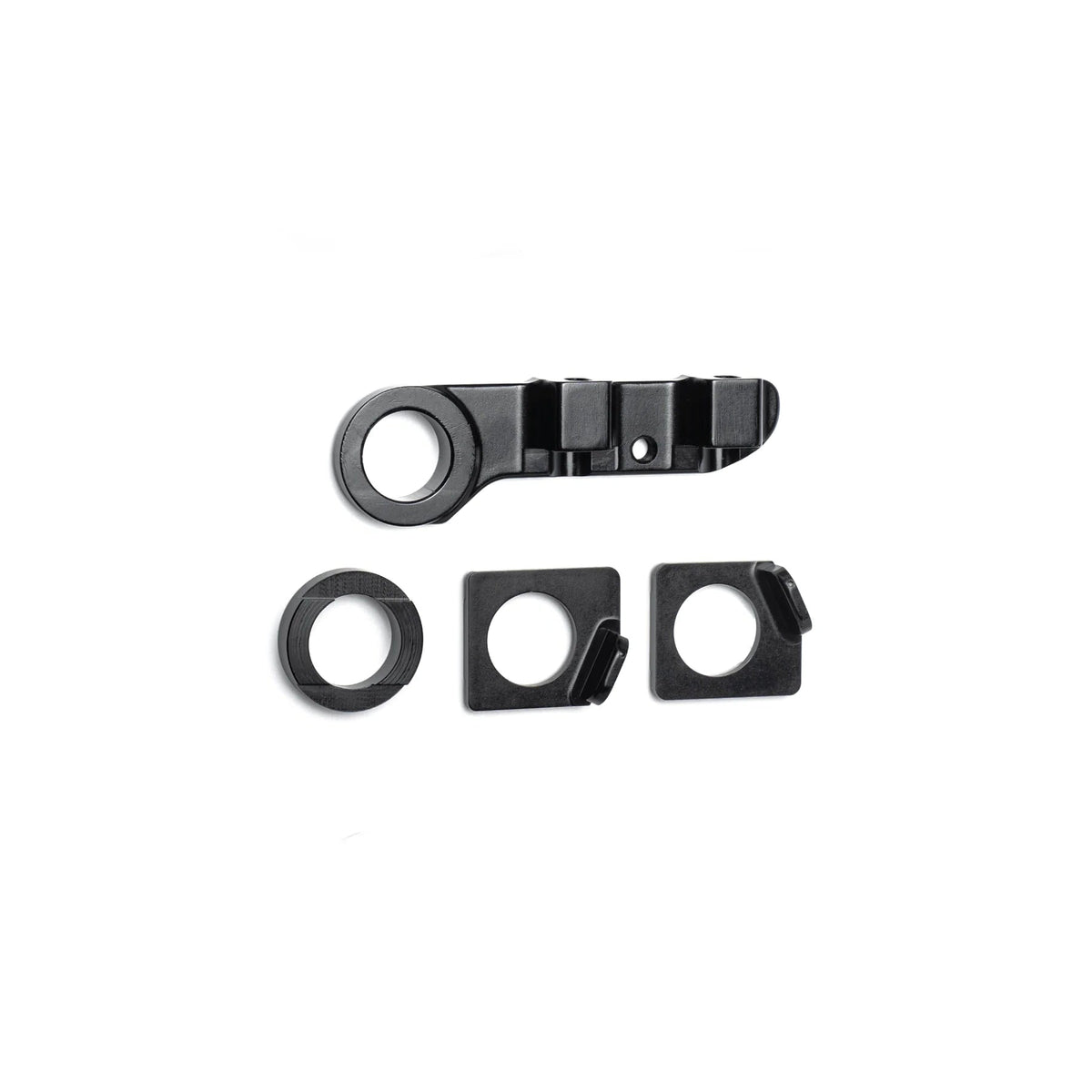 Four black metal components from the DK Zenith Disc Frame Flat Mount Brake/Axle Hardware Kit are arranged on a white background, including one elongated thru-axle piece with holes and three smaller square and circular disc brake hardware pieces.