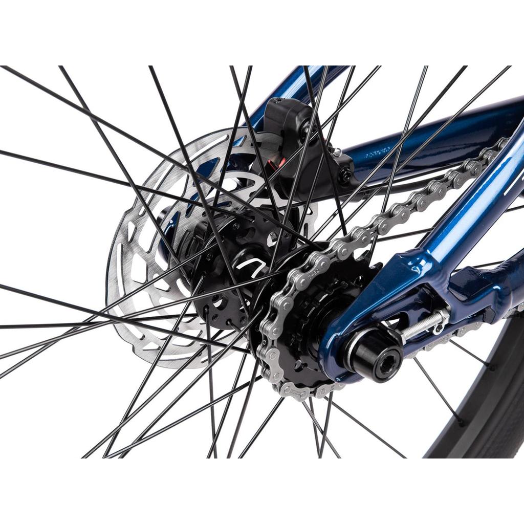Close-up of the Radio Raceline Quartz Pro Disc 24 Inch Bike’s rear wheel, showing disc brake rotor, chain, gear cog, spokes, and a blue frame with race-ready geometry.