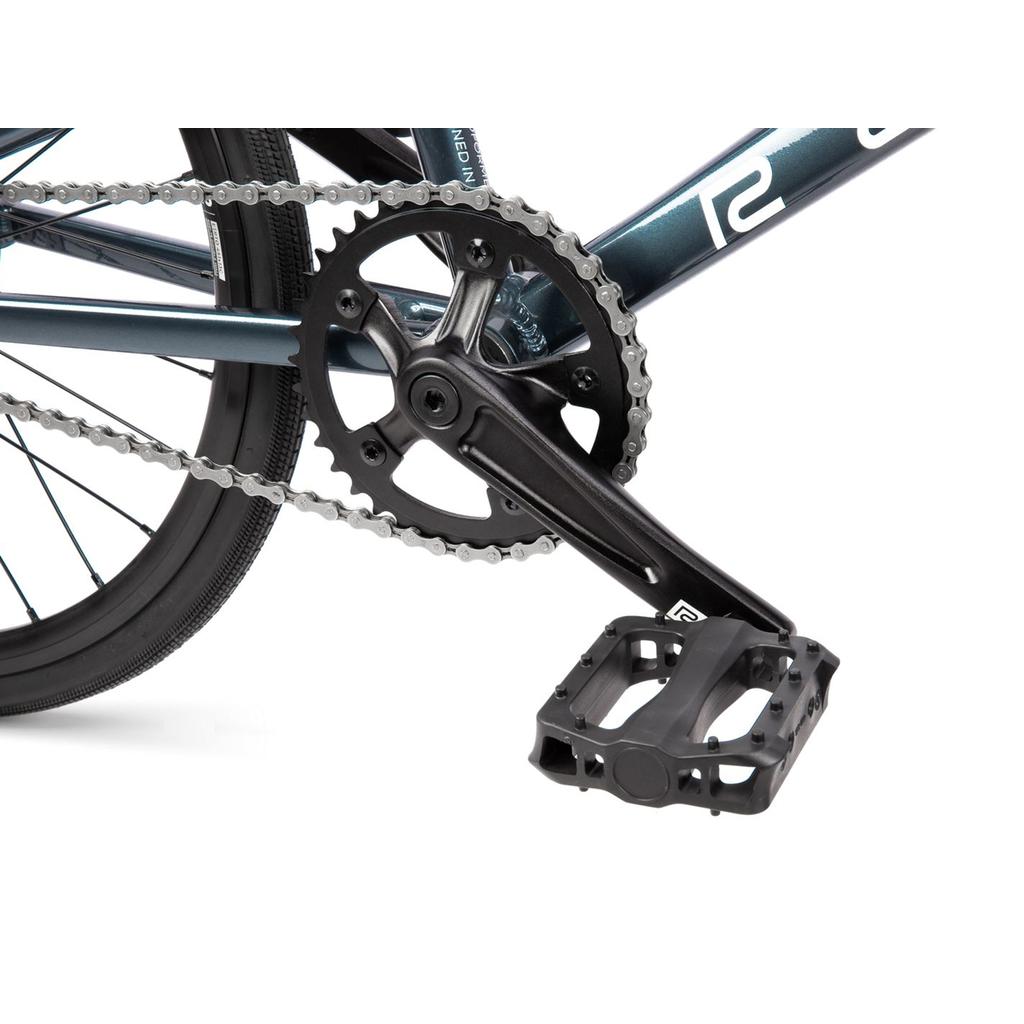 Close-up of the Radio Xenon Junior Disc 20 Inch Bike’s crankset, chainring, chain, and pedal, showing part of its hydroformed 6061-T6 alloy frame and rear wheel fitted with Tioga Power Block tyres.