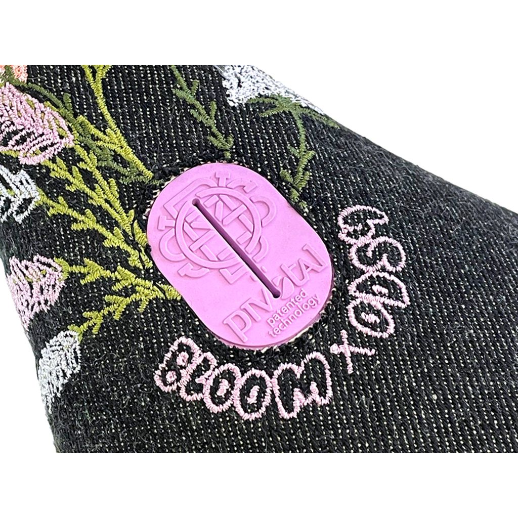 Close-up of a dark fabric with embroidered flowers and a pink, oval-shaped Odyssey Bloom Pivotal Seat label.