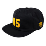 Gear up for Back to School 2025 with the Odyssey 85 Cap—a stylish black 5-panel hat featuring a bold yellow "85" on the front and a small yellow embroidered emblem on the side.