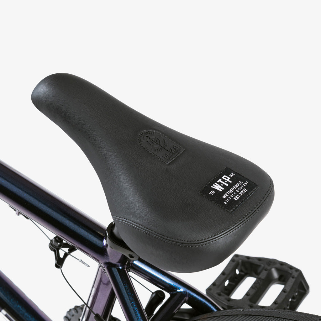 A close up of the seat and Eclat Surge pedals of the Wethepeople CRS 20 Inch Bike.