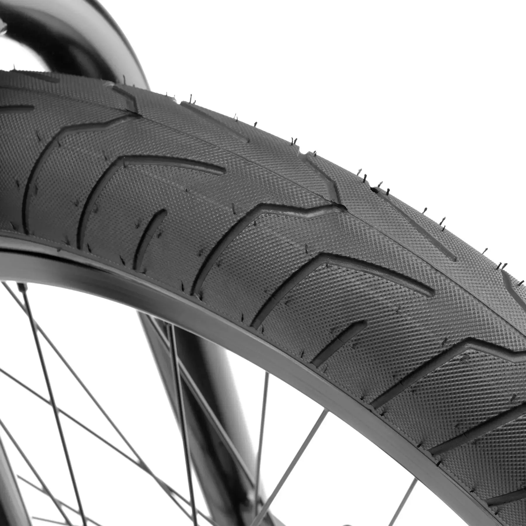 Close-up view of the Kink Whip 20 Inch Bike (2026) showing its black BMX tire with textured tread, visible spokes, and durable sealed bearings for smooth riding.