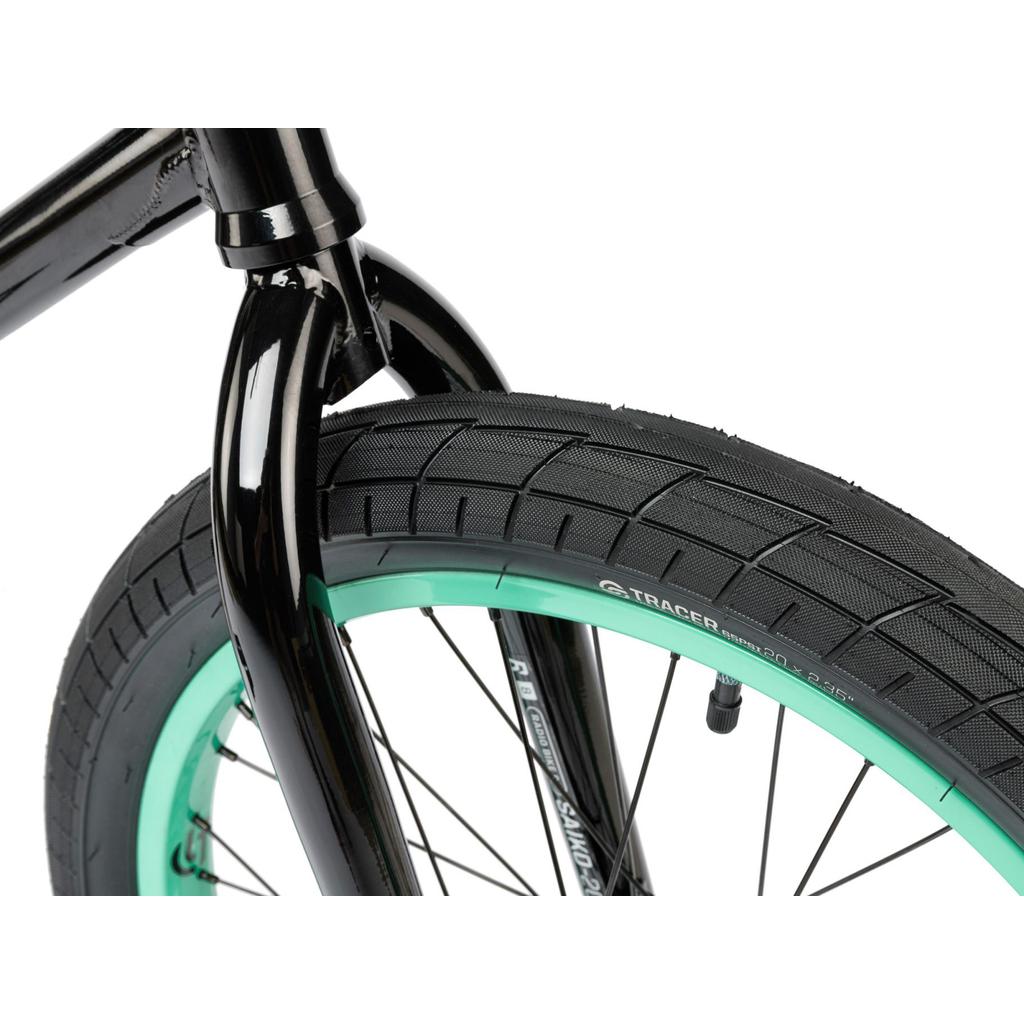 Close-up of a black fork and wheel with a black tire and green sidewall, featuring Salt Tracer Tyres, shown against a white background—designed for the Radio Saiko 20 Inch Bike.