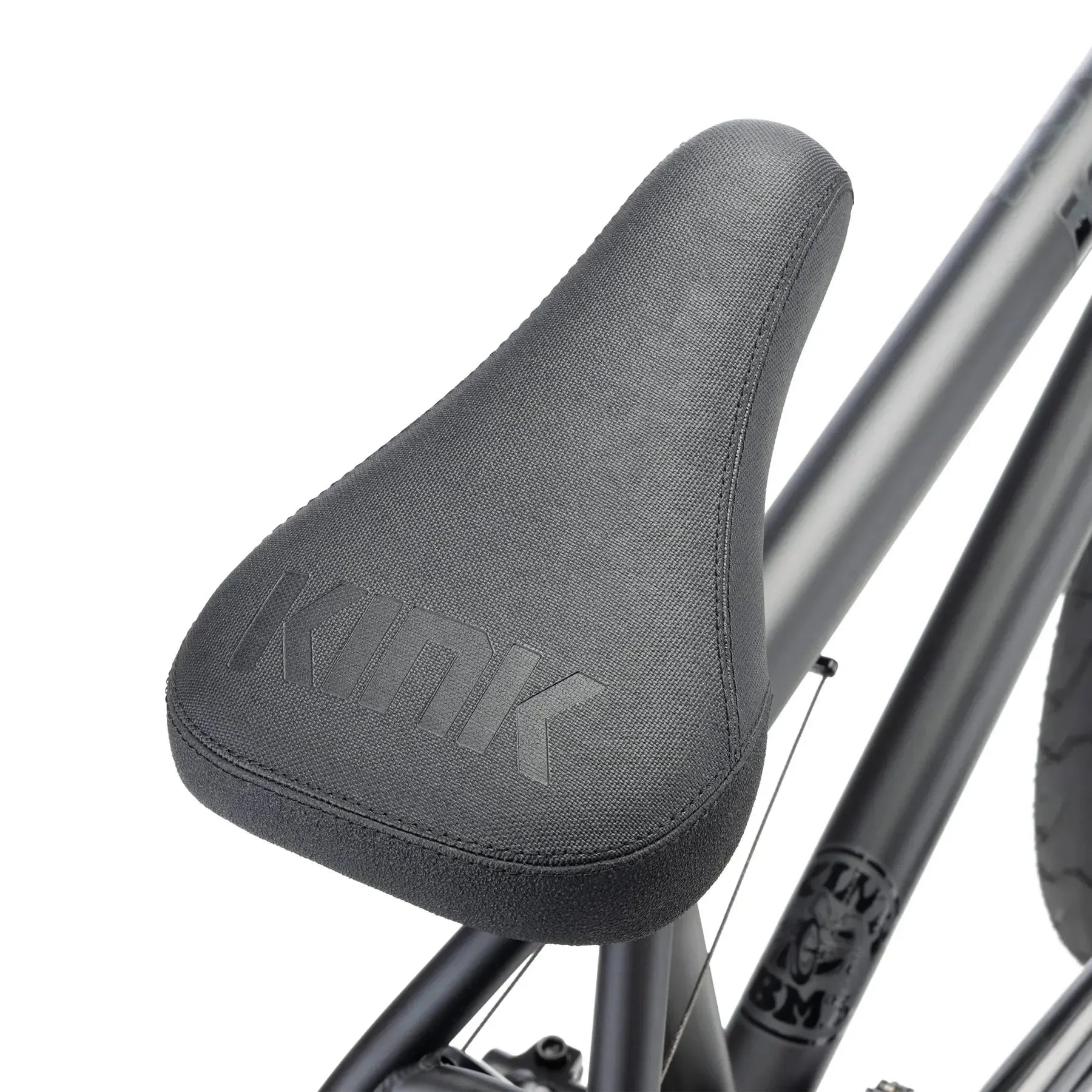 Close-up of a black bicycle seat with "KINK" embossed on it, attached to the matte black Kink Whip 20 Inch Bike (2026) frame crafted from durable 4130 chromoly.