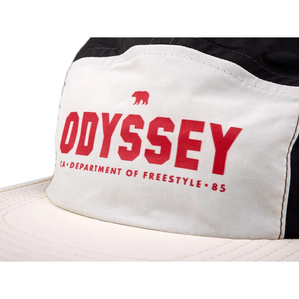 A close-up of the Odyssey Campus Cap, a black and white 5-panel hat featuring "ODYSSEY" and "DEPARTMENT OF FREESTYLE 85" printed in red on the front panel.
