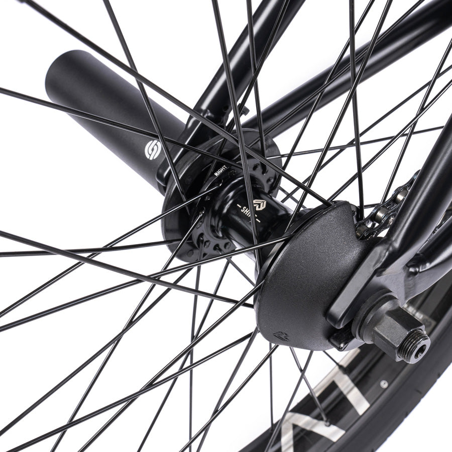 A close up view of a black bicycle wheel featuring the Wethepeople Trust 20 Inch Cassette Bike with Hybrid Technology.