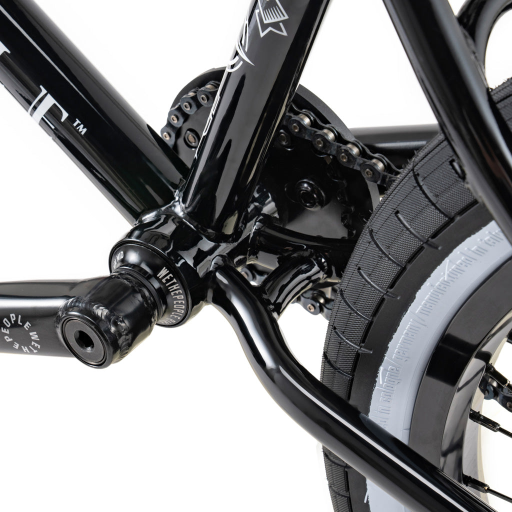 A close up of a black bicycle with white wheels featuring the Wethepeople Battleship 20 Inch BMX Bike.