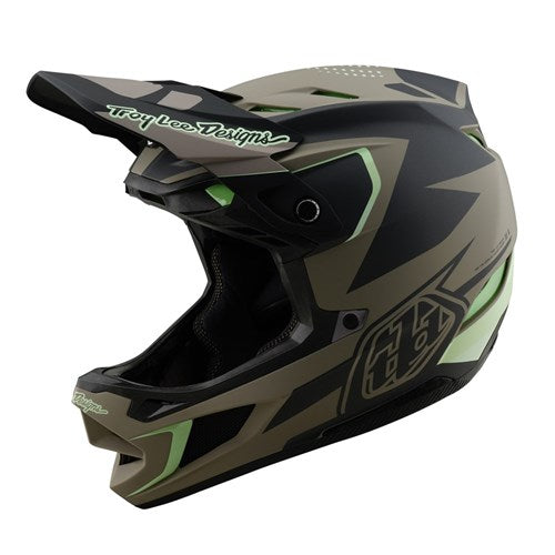 The TLD 25.1 D4 Composite Helmet (MIPS) in Optic Timber, a matte black and green full-face motocross helmet with angular patterns and visor features "Troy Lee Designs" text on the edge. It offers enhanced safety with MIPS protection for improved impact resistance.