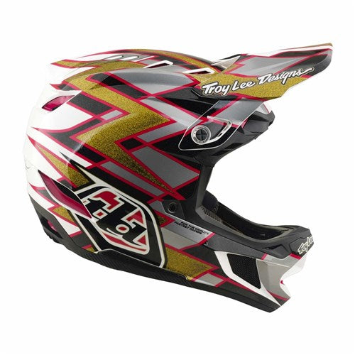 Introducing the TLD 26.2 D4 Composite Helmet / MIPS Flush Black: a full-face motocross helmet featuring striking red, gold, black, and white geometric graphics with “Troy Lee Designs” text on the visor. Equipped with advanced MIPS protection, this helmet offers enhanced safety out on the trail.