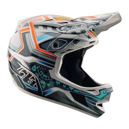 The TLD 25.2 D4 Composite Helmet MIPS Lowrider Grey is a full-face motocross/BMX helmet with gray, orange, and teal geometric patterns and "Troy Lee Designs" branding on the visor and chin.
