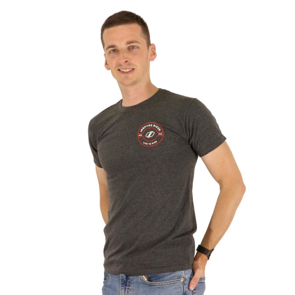 Man wearing the Inspyre Icon T-Shirt in dark gray, featuring a small circular logo on the left chest, and blue jeans, standing against a plain white background.
