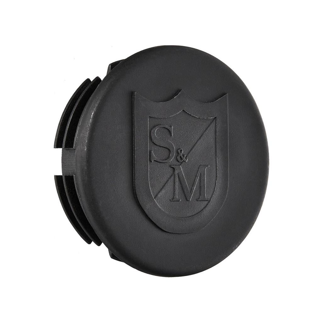 The S&M End Cap Slide Pipe Rail is a black circular cap with grooved edges, featuring an embossed shield logo with "S & M" letters, perfect as a replacement end cap or rail accessory.