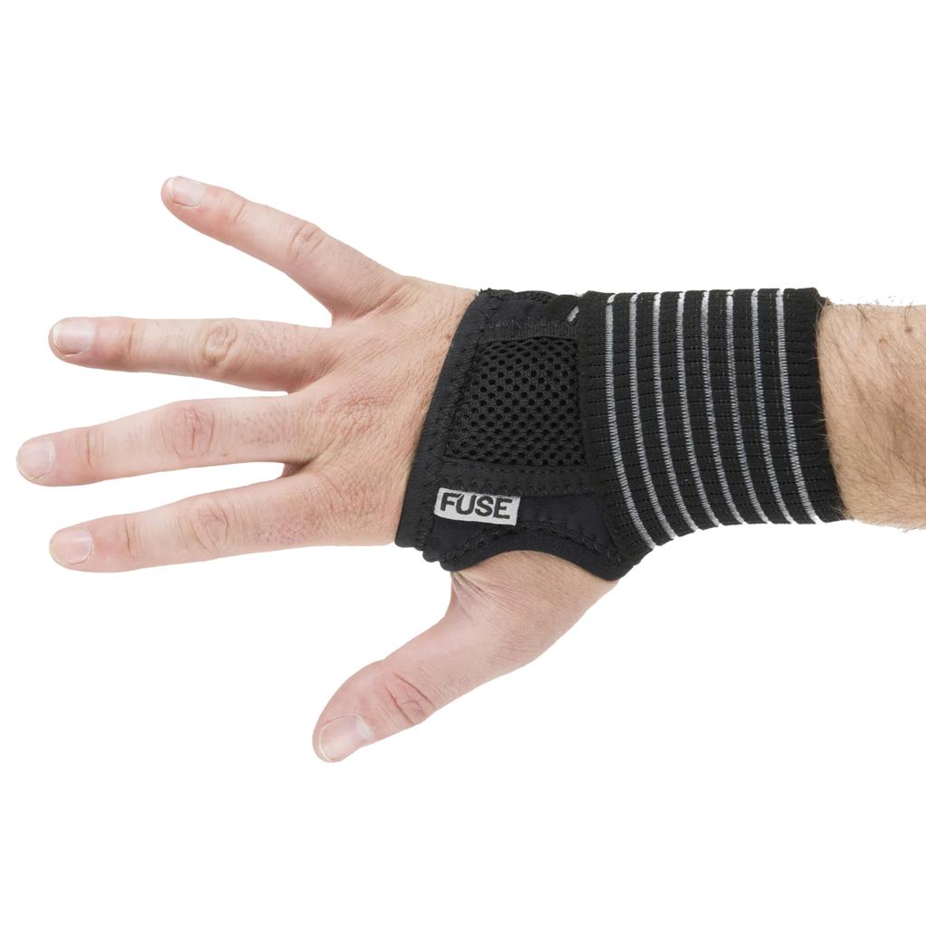 A left hand wears a black and gray Fuse Alpha Pro Wrist Guard, made from anti-bacterial neoprene, against a white background.
