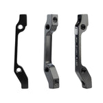 Three views of the Promax PM for IS Disc Brake Adaptor in black aluminium alloy, showing mounting holes and engraved markings for front 180mm or rear 140mm rotor compatibility.
