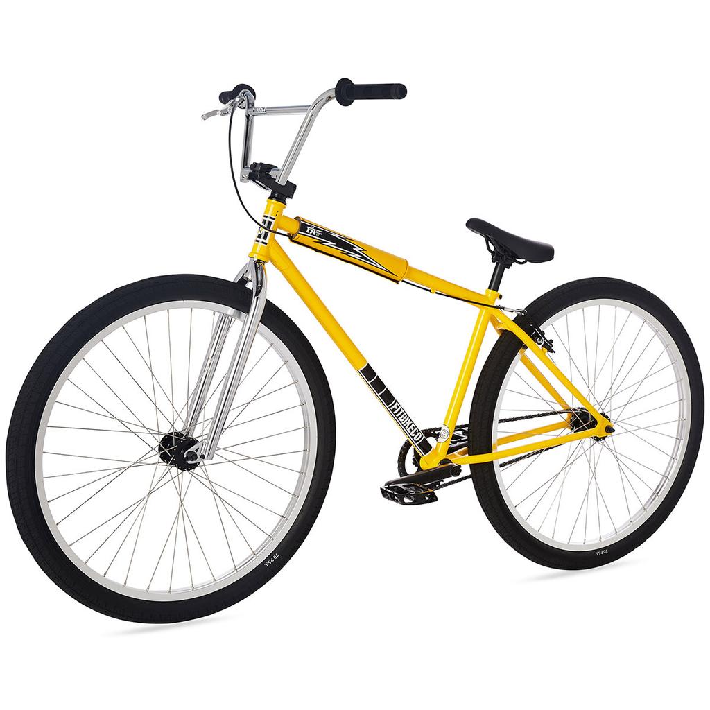 The Fit CR29 Inch Bike (2023) is a yellow BMX cruiser featuring black handlebars, a black seat, silver spokes, and a minimalist frame design, displayed against a white background.