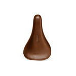 The Eclat Exile Pivotal Seat is a brown leather BMX seat with a smooth surface, a small vertical slot near the center, and an embossed brand logo near the bottom.
