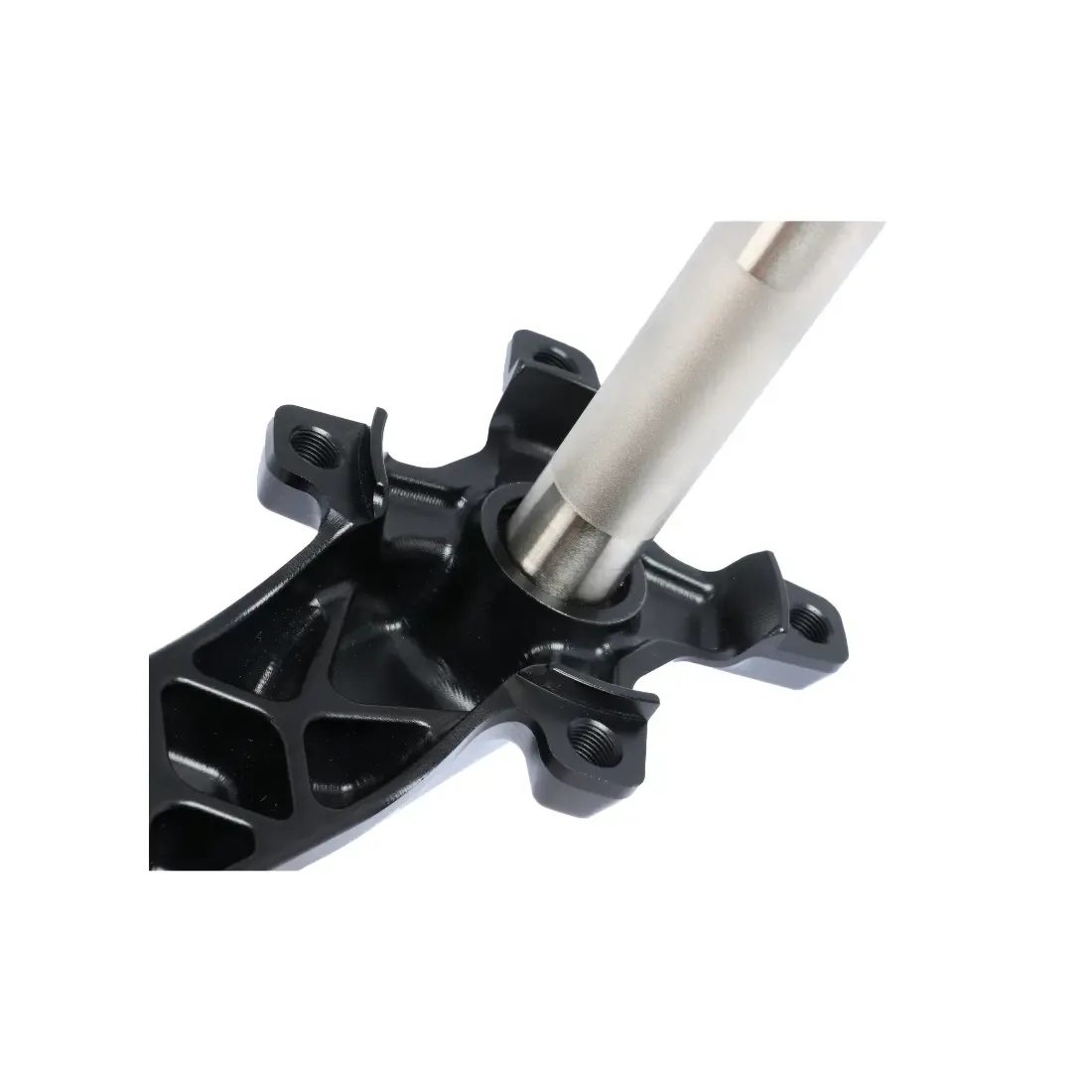 Close-up of a Pride Newton SX Youth Crankset inserted into a black, machined component with multiple mounting holes, set against a white background.