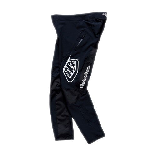 TLD 26.1 Sprint Pro Pants (Youth) in Mono Black, featuring a white Troy Lee Designs logo on the thigh, zip pocket, 4-way stretch fabric, and ratchet waistband closure, shown laid flat on a white background.