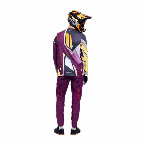 A person wearing TLD 26.1 Sprint Pro Pants in Mono Sangria, featuring 4-way stretch fabric, stands facing away from the camera against a white background.