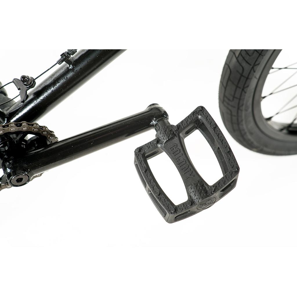 Close-up of a black pedal attached to the crank arm of the Colony Prody Pro 20 Inch Bike, with the rear wheel and chain visible against a white background—ideal for mid school BMX enthusiasts.