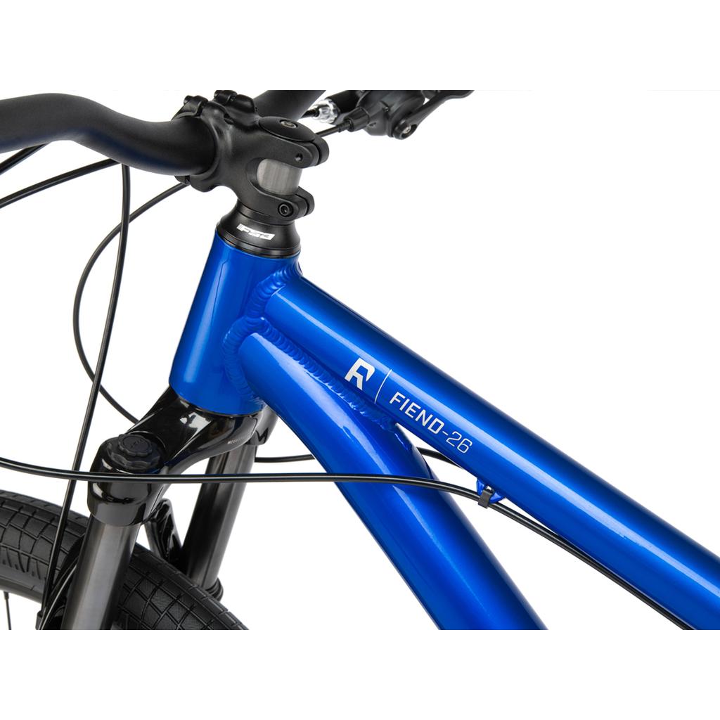Close-up view of the 6061-T6 alloy frame and handlebars on a blue Radio Fiend 26 Inch Bike against a white background.