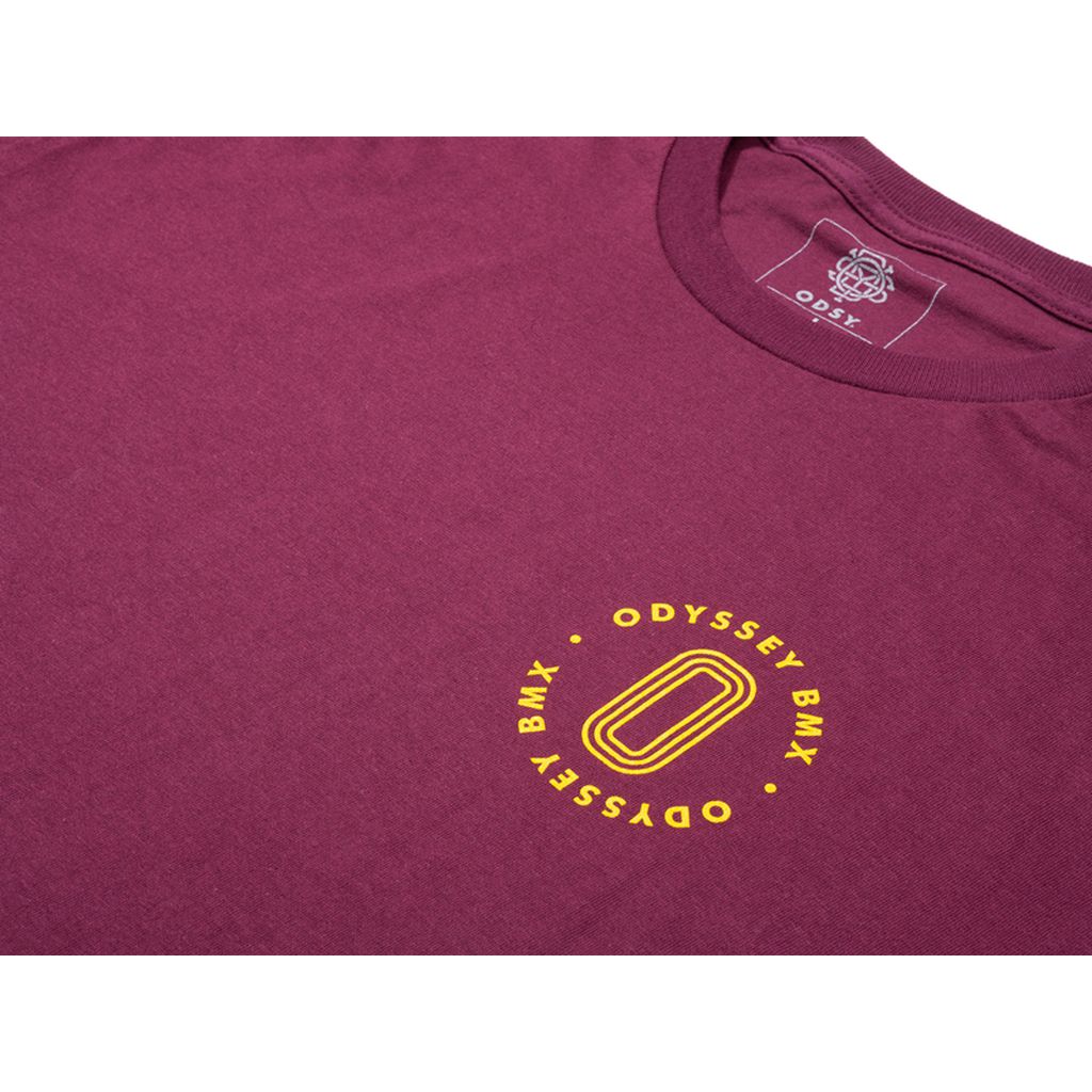 The Odyssey Athens T-Shirt is a maroon shirt featuring a small yellow "ODYSSEY BMX" logo and design on the front, along with a logo on the inside neck label.