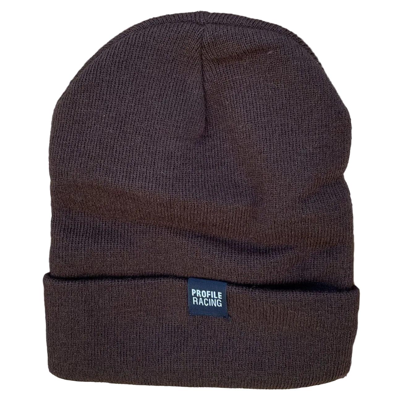 The Profile Woven Label Beanie is a brown knit hat with a folded brim and a small "Profile Racing" woven label, union made in the USA and shown on a rustic wooden background.