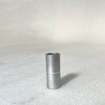 A small, cylindrical metal piece, resembling the Profile 19mm Tube Spacer (53mm), stands upright on a light textured surface.