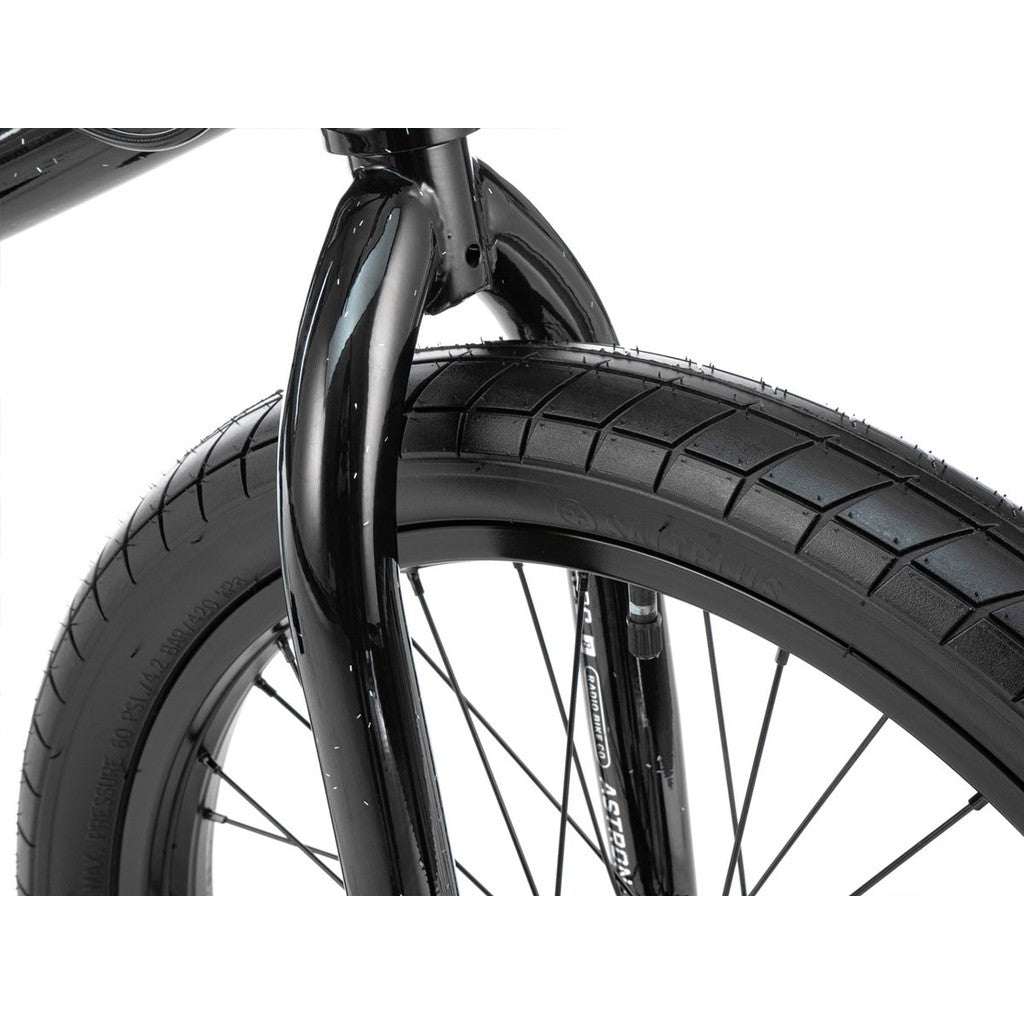 Close-up view of a Radio Astron FS 20 Inch Bike's front wheel and fork. The tire showcases a textured tread pattern, while the sleek black fork boasts a glossy finish, perfectly complementing the full chromoly frame.