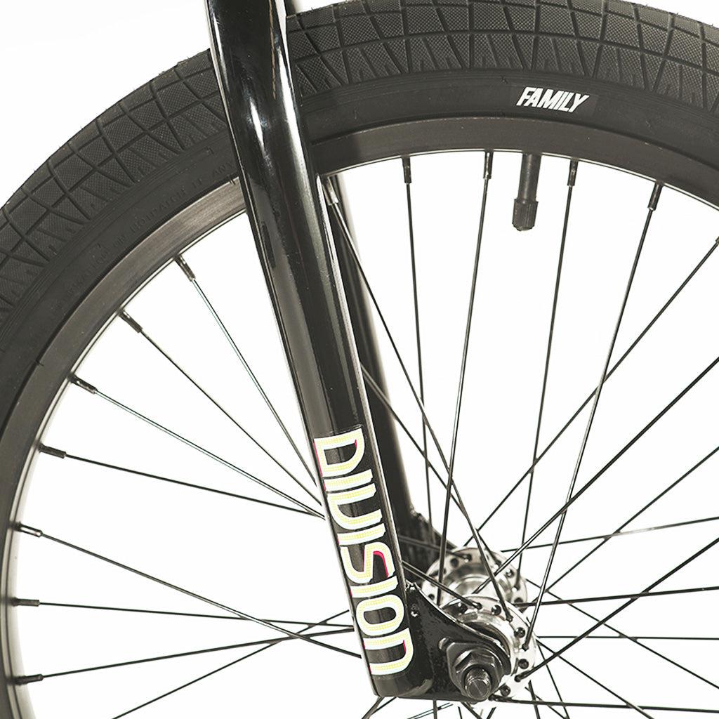 Close-up of the front wheel of a black Division Blitzer 20 Inch bike, featuring "Division" written on the fork and "Family" on the tire. The sturdy hi-tensile frame ensures durability for every ride.