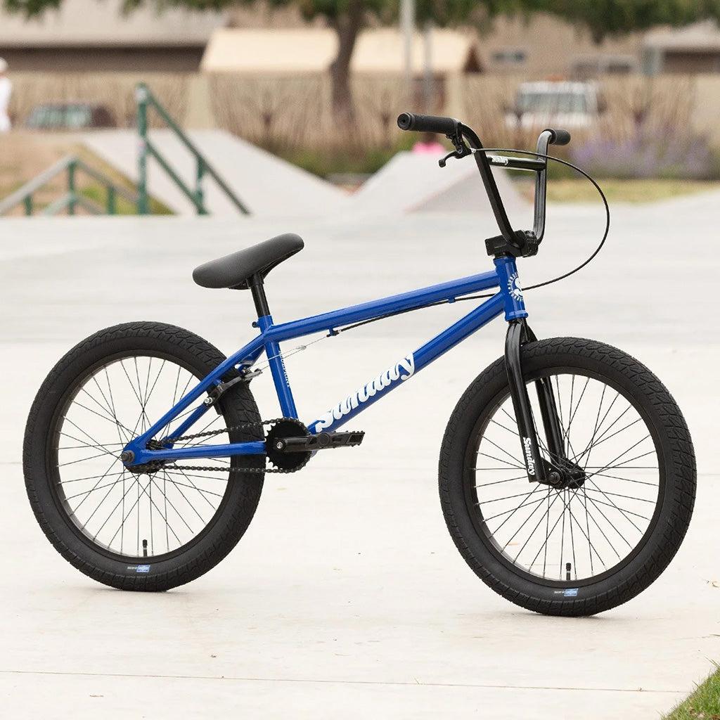 A beginner BMX bike, the Sunday Blueprint 20 inch Bike, parked in a park.