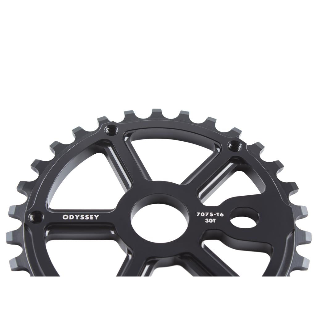 A close-up of the Odyssey Utility Pro Guard Sprocket in black, featuring a strong plastic guard, central hole, and durable teeth—perfect for protecting freestyle BMX chains.