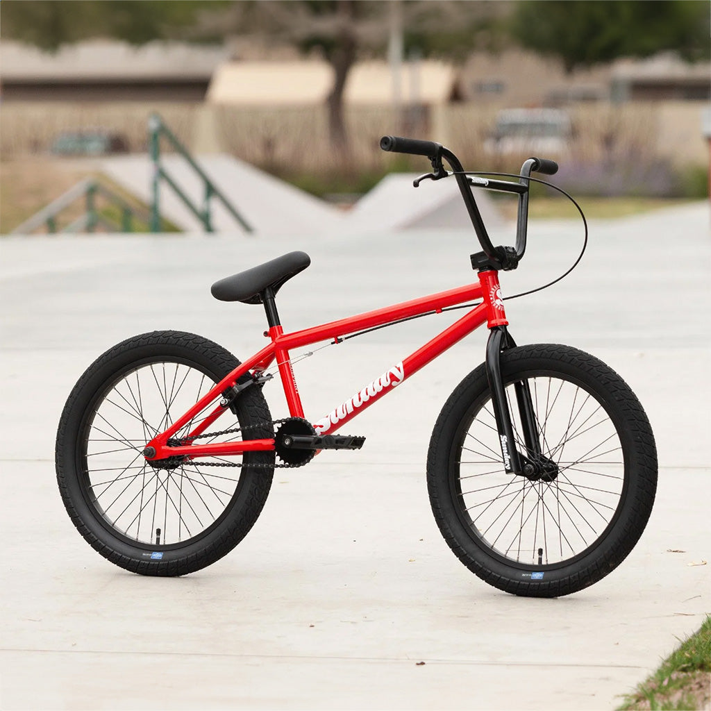 A red BMX bike, specifically the Sunday Blueprint 20 inch Bike model, parked in a parking lot.