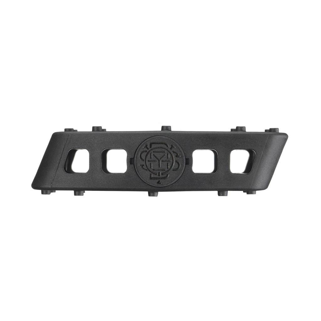 The Odyssey Twisted PC Pro Pedals are black, high-strength nylon composite pedals with four rectangular cutouts, a central circular emblem with a geometric design, a textured surface, and raised details inspired by BMX style.