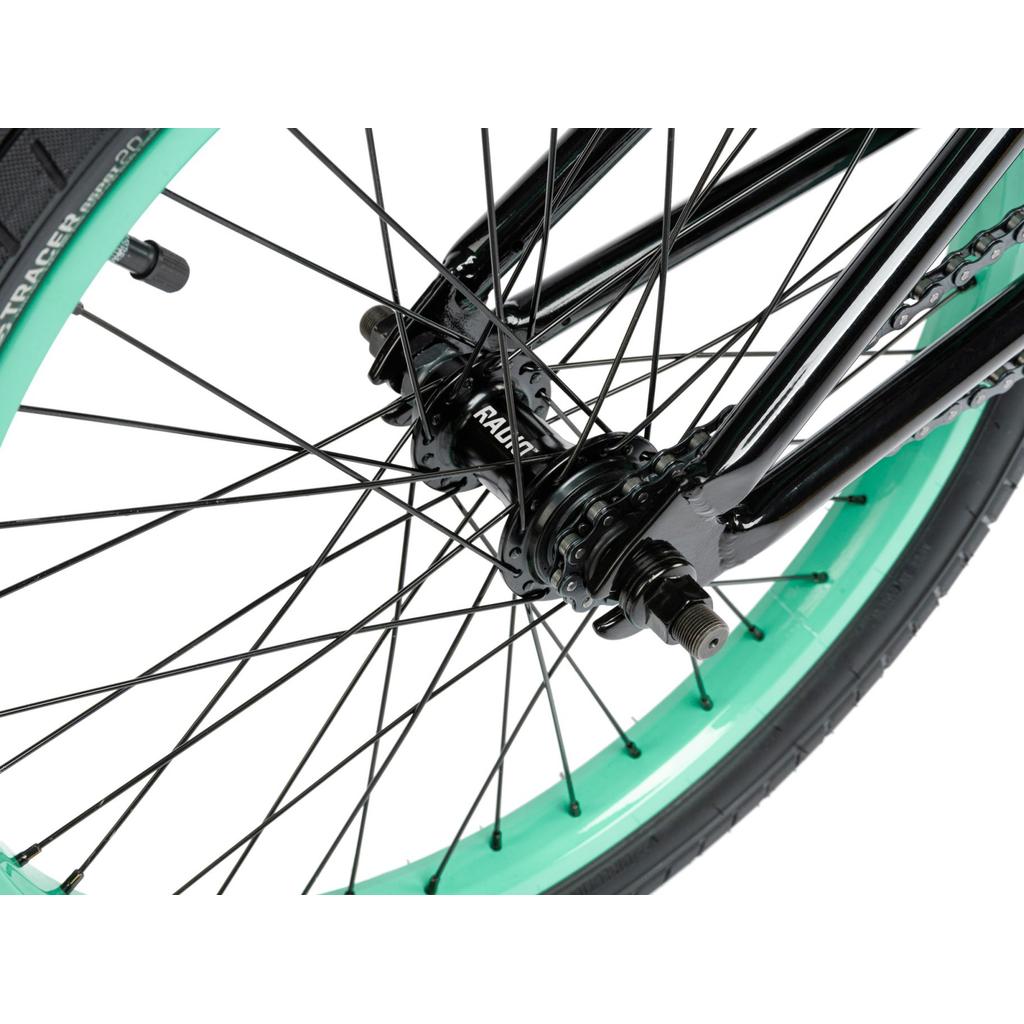 Close-up of the Radio Saiko 20 Inch Bike's wheel featuring black spokes, a black hub, and a green rim with Salt Tracer Tyres against a white background.