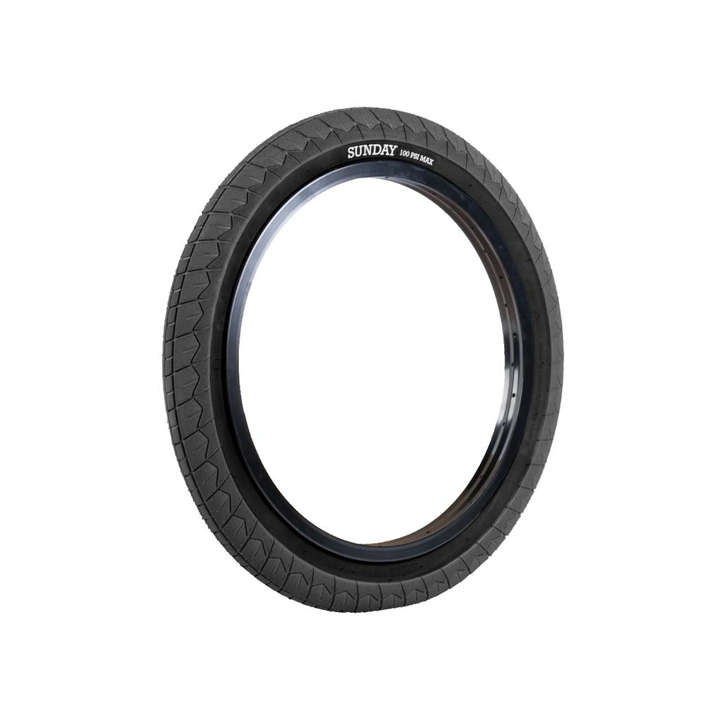 The Sunday Current V2 Tyre (Each) in black stands upright against a white background, showcasing a grippy tread and the "SUNDAY" logo on the sidewall—combining style, function, and affordability for BMX bikes.