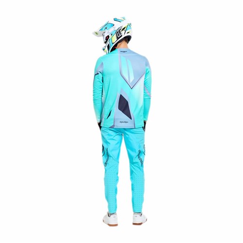 A person wearing the TLD 26.1 Sprint Pro Jersey / Lowrider Real Teal motocross outfit and helmet stands with their back to the camera against a white background.