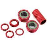 The MCS Euro BB Set features red metal automotive parts: two threaded cups labeled "MCS RACING," a cylindrical sleeve, and four washers, resembling those in Euro bottom bracket assemblies with sealed cartridge bearings. Displayed on a white background.