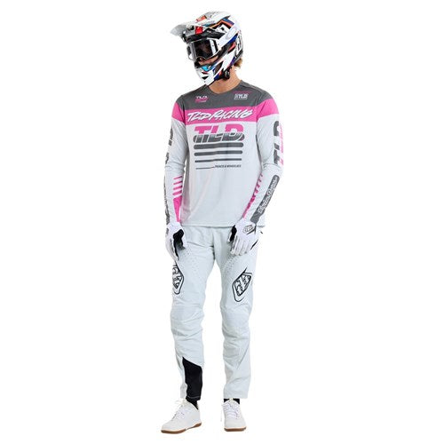 A person clad in a stylish Troy Lee Designs motocross set, featuring a helmet, gloves, and the vibrant TLD 25.1 Sprint Jersey in Fifty-50 Chalk—ideal for race weekends.