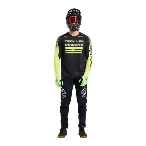 A person wearing a TLD 25.2 Sprint Jersey / Segment Black motocross outfit, including helmet, gloves, pants, and boots, stands facing forward against a white background.