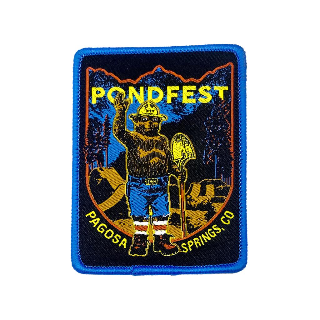The S&M Smokey Pondfest Patch is a rectangular collectible jacket patch showing a bear in work gear with a shovel, "Pondfest" above, "Pagosa Springs, CO" below, and a forest background—great for fans and collectors alike.